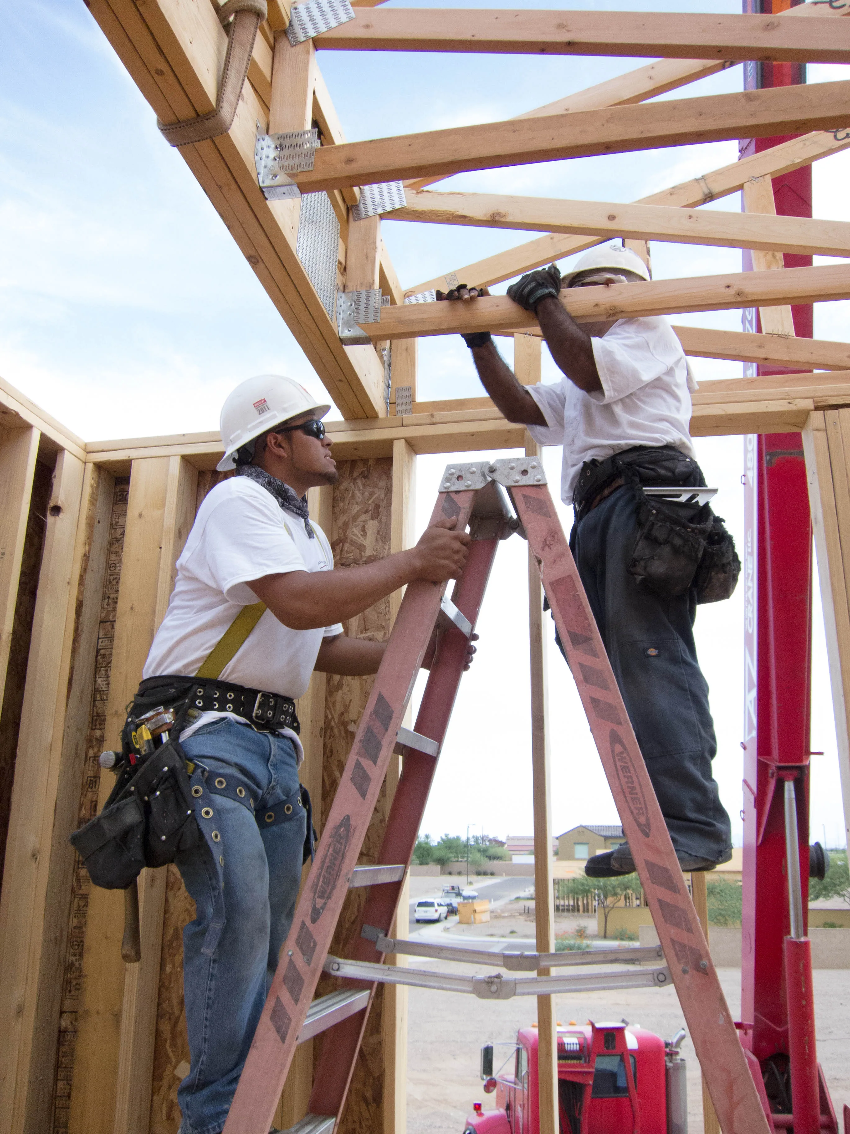 Trabalhadores da construção civil usando equipamento de proteção contra quedas.